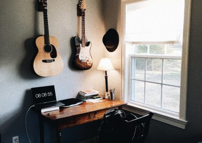 brown acoustic guitar near brown and black electric guitar hanging on wall